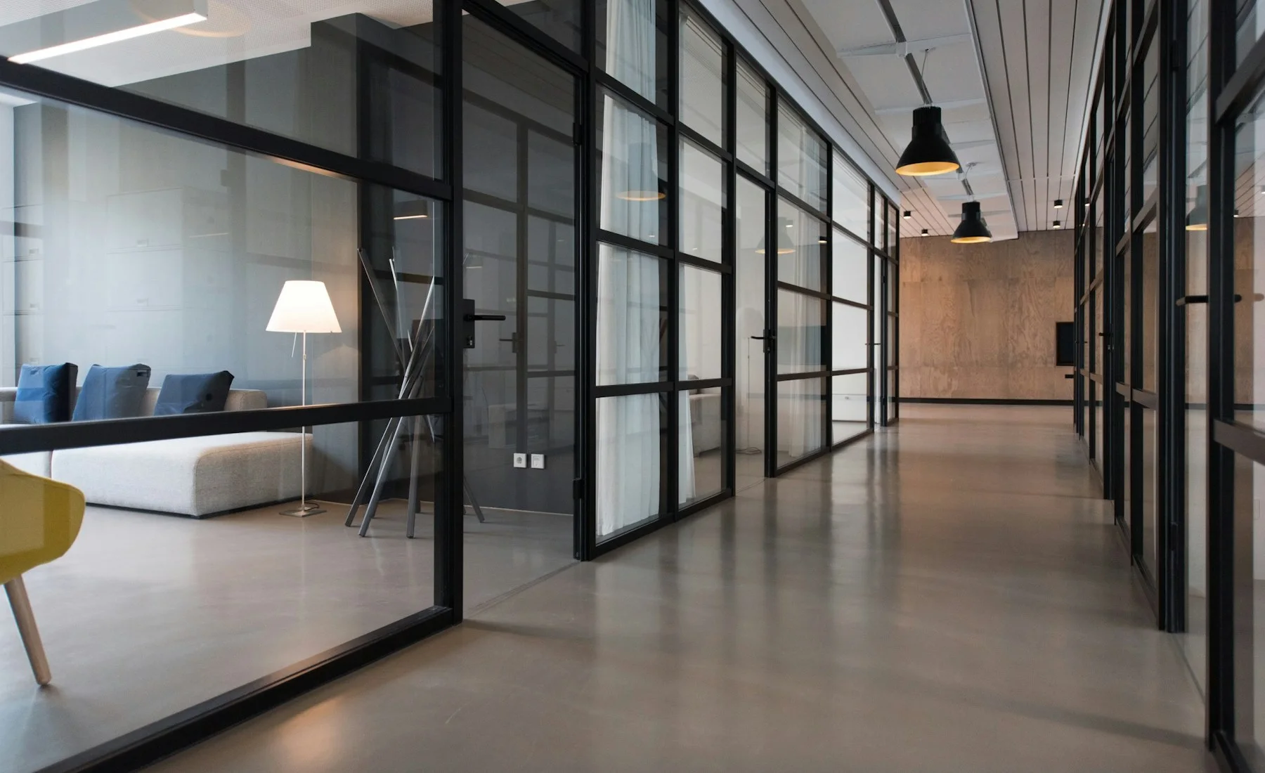 Pasillo de oficinas modernas con salas acristaladas.